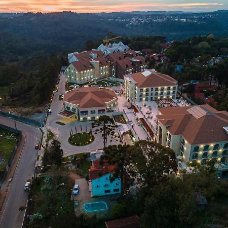 Buona Vitta Gramado Resort & Spa By Gramado Parks Екстер'єр фото The photo shows an aerial view of a hotel complex set in a hilly, wooded area. The buildings feature a mix of architectural styles with several structures, including a central round pavilion. Surrounding the buildings are well-maintained gardens and 