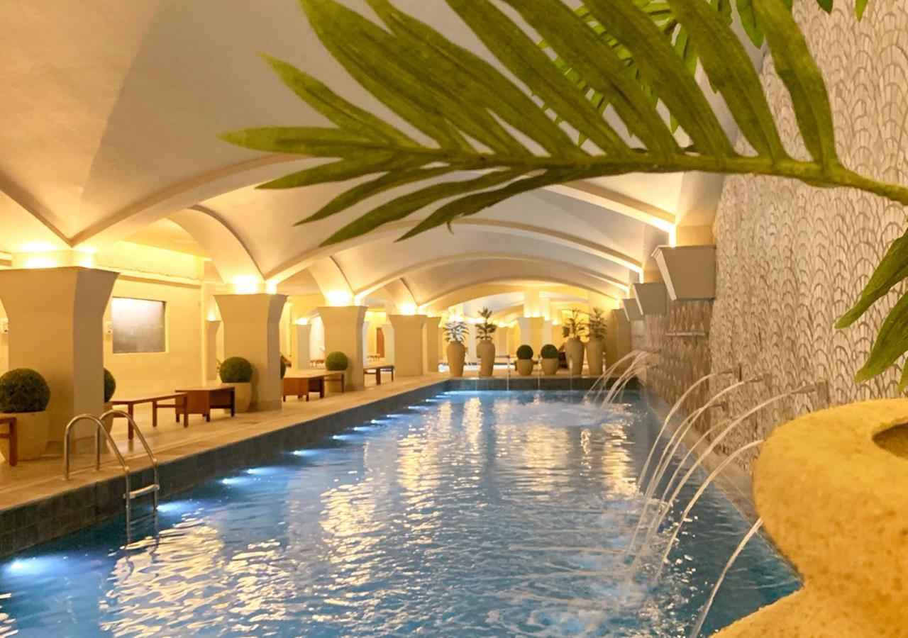 Buona Vitta Gramado Resort & Spa By Gramado Parks Екстер'єр фото The photo shows an indoor swimming pool with a serene and elegant atmosphere. The pool has a calm blue water surface, illuminated by soft lights along its edges. The architectural design features arches in the ceiling, creating an open and spacious f