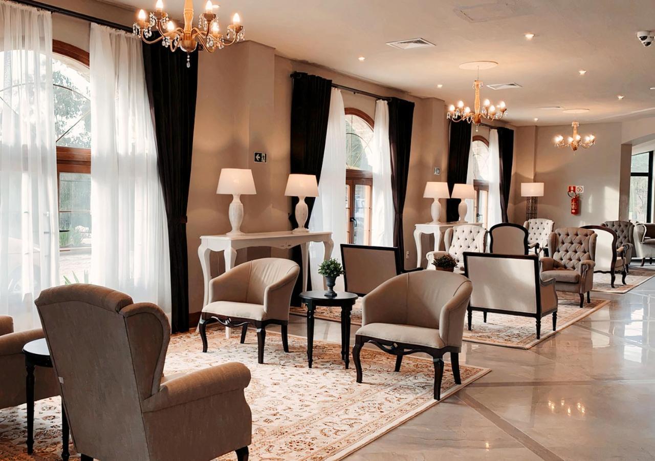 Buona Vitta Gramado Resort & Spa By Gramado Parks Екстер'єр фото The photo depicts a stylish and sophisticated lounge area. It features several elegant chairs and sofas, arranged around small tables on a decorative rug. The room is well-lit with natural light coming in through large windows dressed with flowing wh