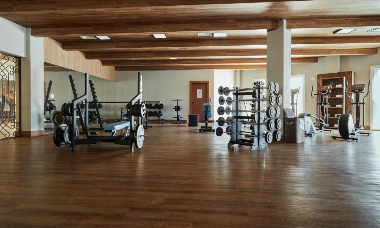 Buona Vitta Gramado Resort & Spa By Gramado Parks Екстер'єр фото The photo shows a spacious gym with a wooden floor and wooden ceiling beams. Various pieces of gym equipment are visible, including weight benches and racks with weights. On one side, there are free weights organized on a rack, while other equipment 