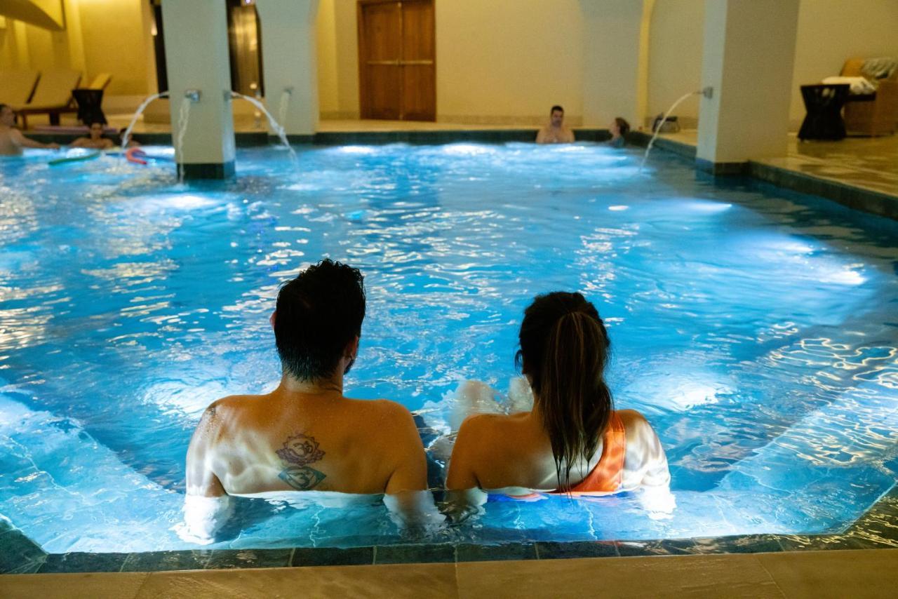 Buona Vitta Gramado Resort & Spa By Gramado Parks Екстер'єр фото The photo shows a couple sitting in a swimming pool with gentle lighting. They are facing away from the camera, appearing relaxed and enjoying their time together. The water is illuminated with a soft blue light, creating a serene atmosphere. In the 
