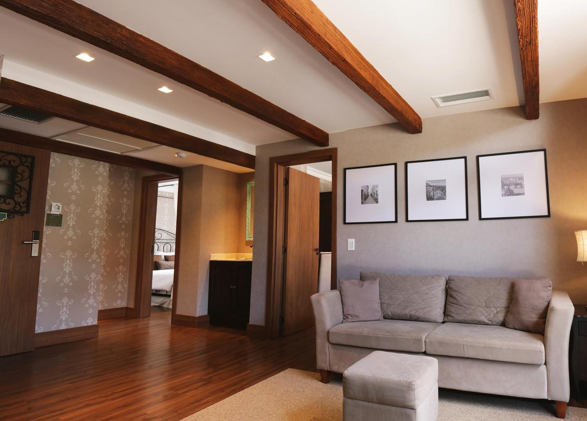 Buona Vitta Gramado Resort & Spa By Gramado Parks Екстер'єр фото The photo showcases a modern living space with a cozy and well-lit atmosphere. There are wooden beams visible on the ceiling, adding a rustic touch. The flooring is a warm-toned wood, contributing to the inviting feel of the room. 

On one side, ther