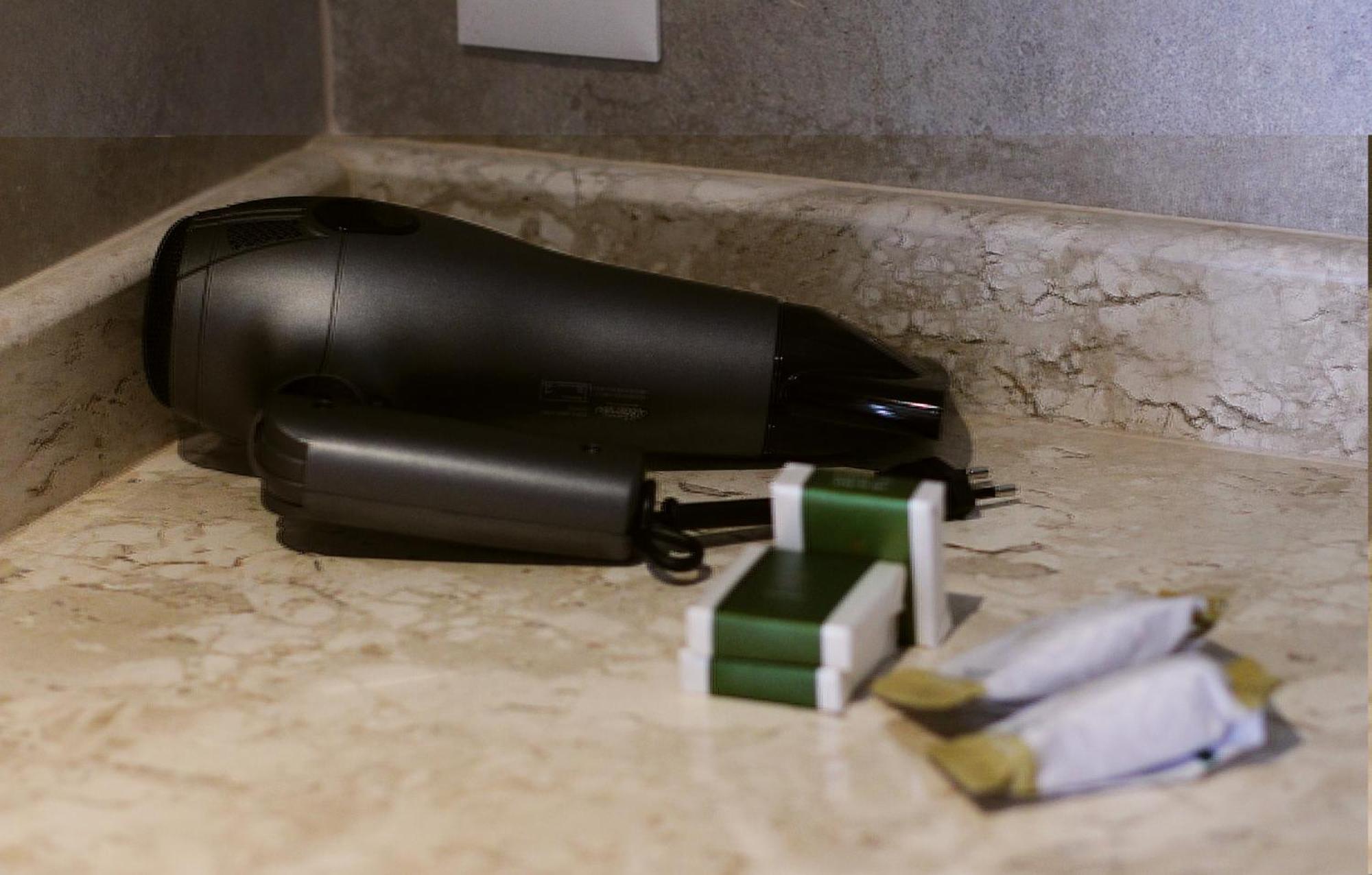 Buona Vitta Gramado Resort & Spa By Gramado Parks Екстер'єр фото The photo shows a black hairdryer placed on a marble countertop. Next to the hairdryer, there are two wrapped items, likely toiletries, with green and white packaging. Additionally, there are two more items, also wrapped, which appear to be in simila