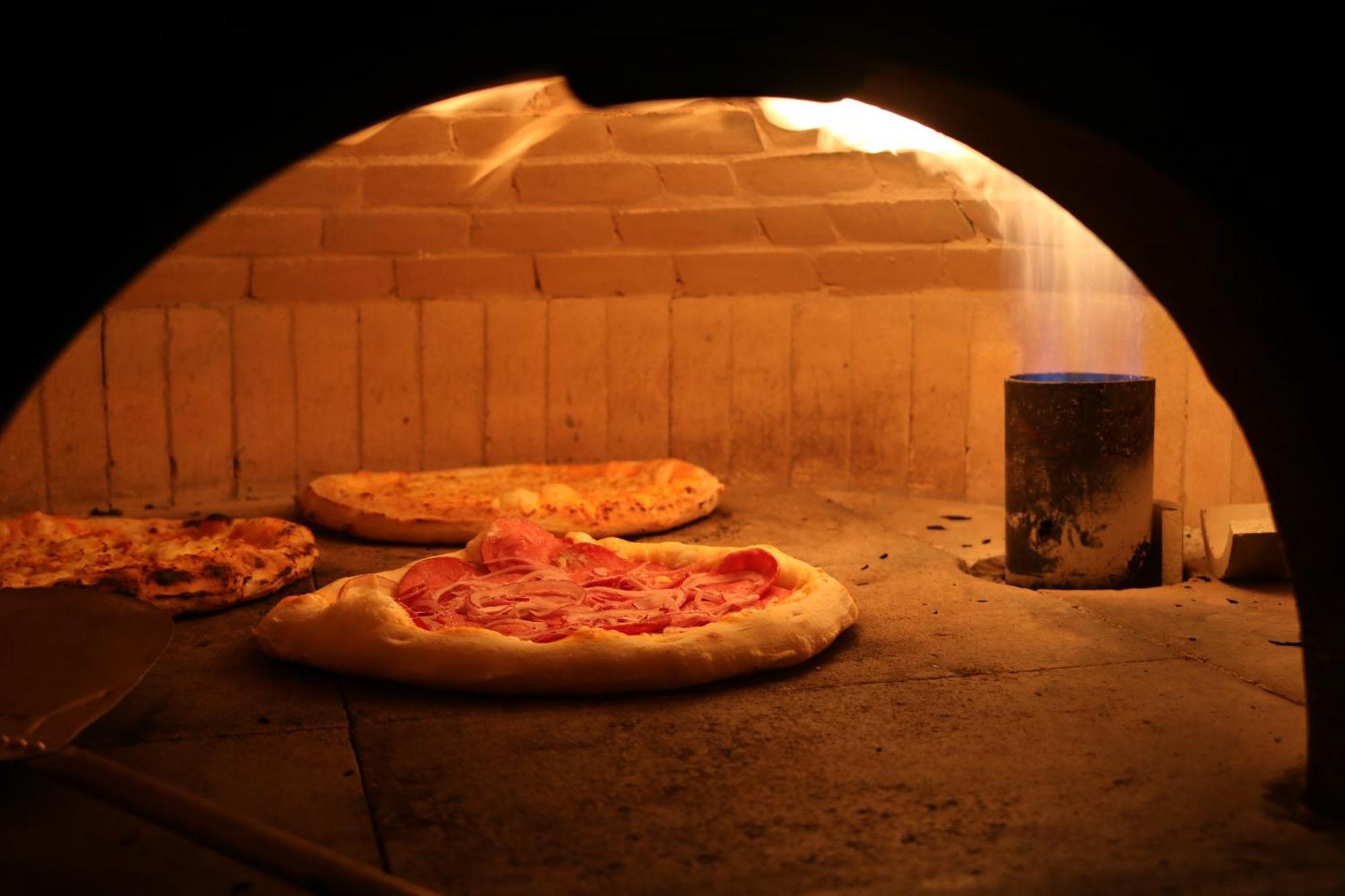 Buona Vitta Gramado Resort & Spa By Gramado Parks Екстер'єр фото The photo shows a traditional pizza oven. Inside the oven, there are several pizzas placed on the stone surface. The pizzas appear to have various toppings, including what looks like cheese and possibly pepperoni. The oven has a warm, glowing ambianc