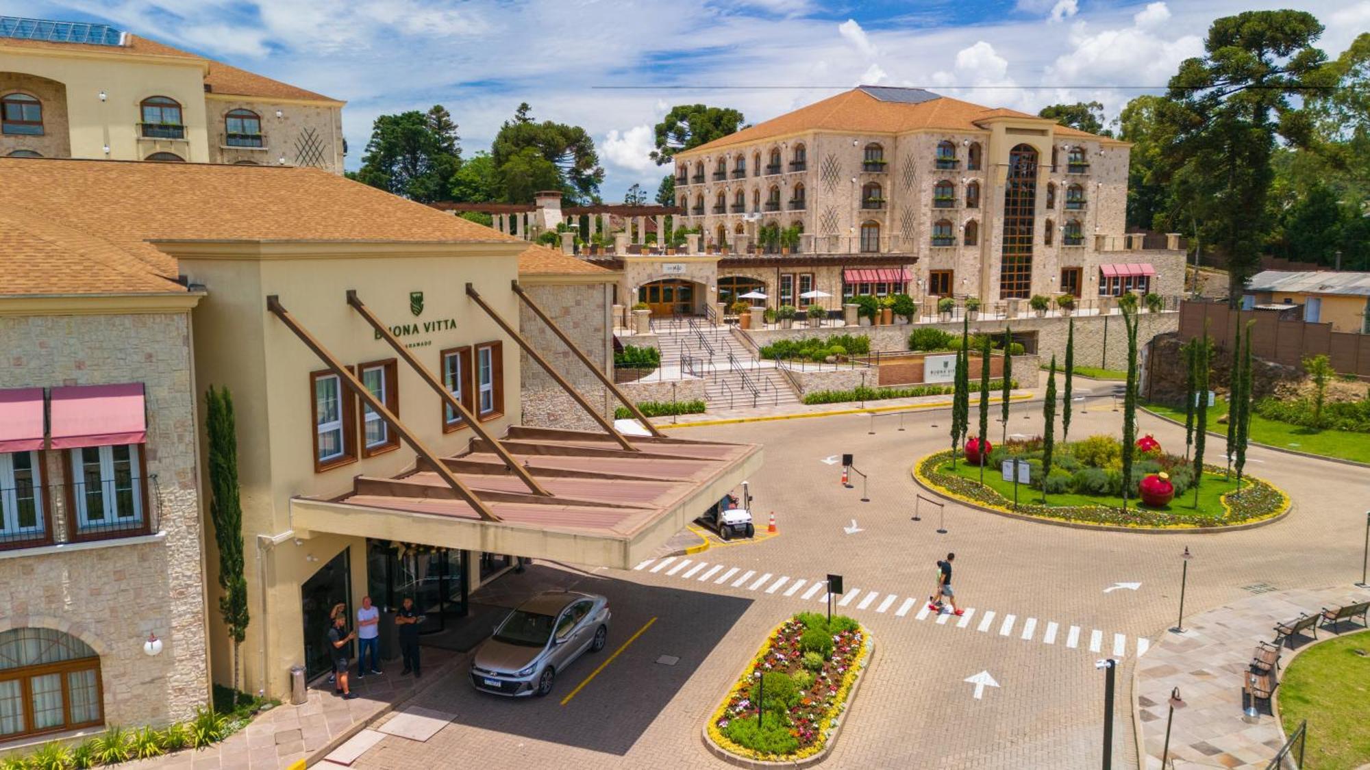 Buona Vitta Gramado Resort & Spa By Gramado Parks Екстер'єр фото The photo shows a luxurious hotel or resort entrance, featuring a modern yet elegant architectural design. In the foreground, there is a covered entrance where vehicles are likely dropping off guests. The building has a stone facade and a welcoming e